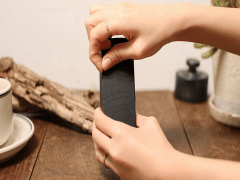 木のテーブルで、両手を使ってBITOKUの黒い化粧箱を開封する様子