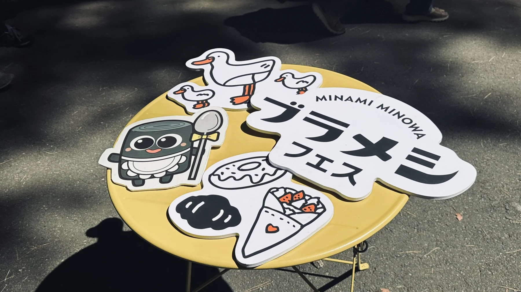 ブラメシフェス2025のロゴを配した丸い手持ちパネル