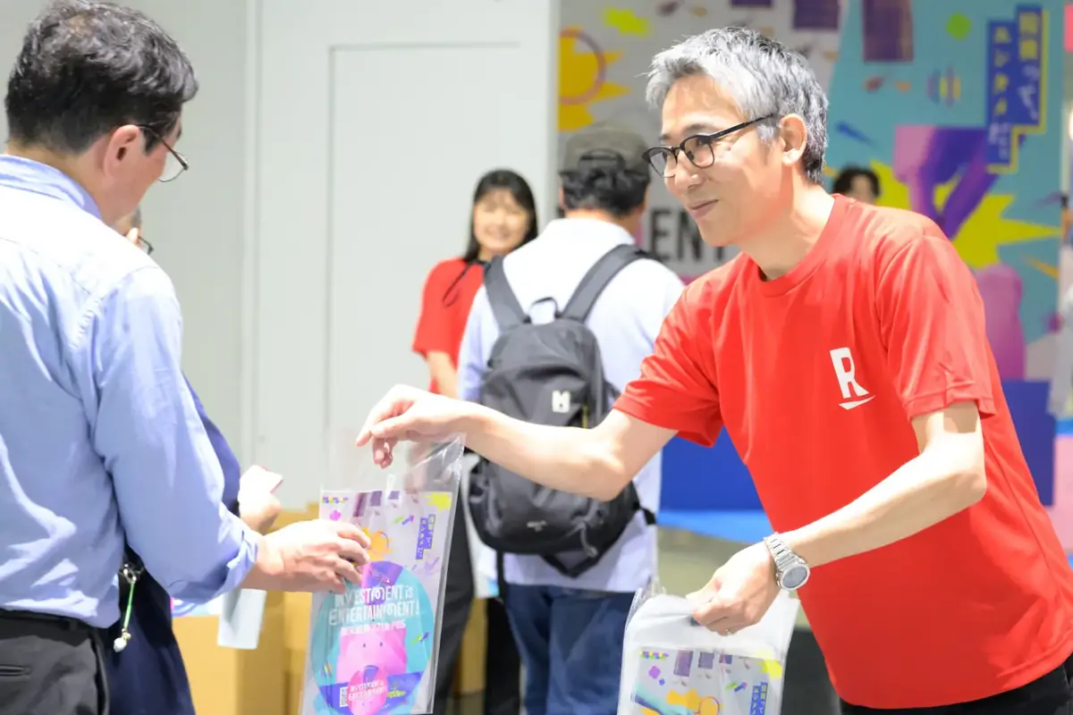 会場でパンフレットの入った袋を手渡すスタッフ