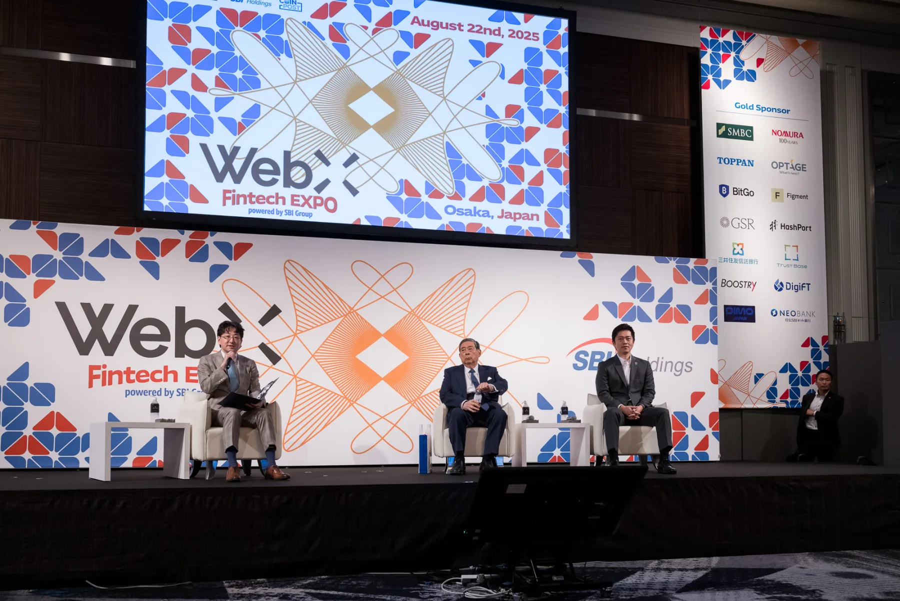 WebX Fintech EXPOのステージ。キービジュアルを背景に登壇者が対談する様子