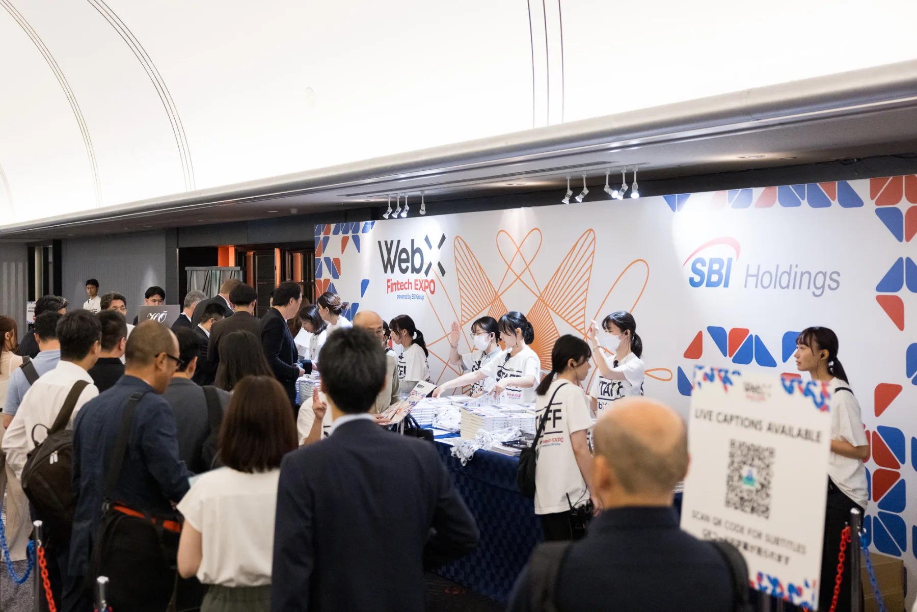 WebX Fintech EXPOの受付。キービジュアルを展開した壁面の前に来場者が並ぶ様子
