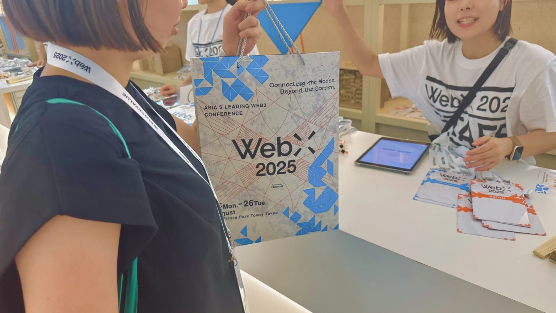 WebX 2025の受付。ロゴと幾何学模様を配したカウンター