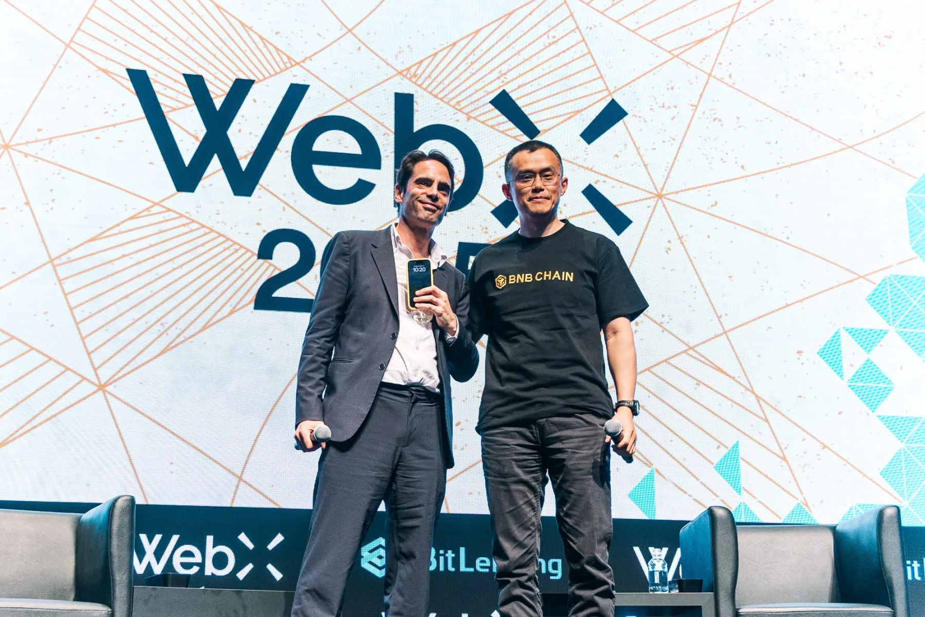 WebX 2025のキービジュアルを背景に立つ登壇者
