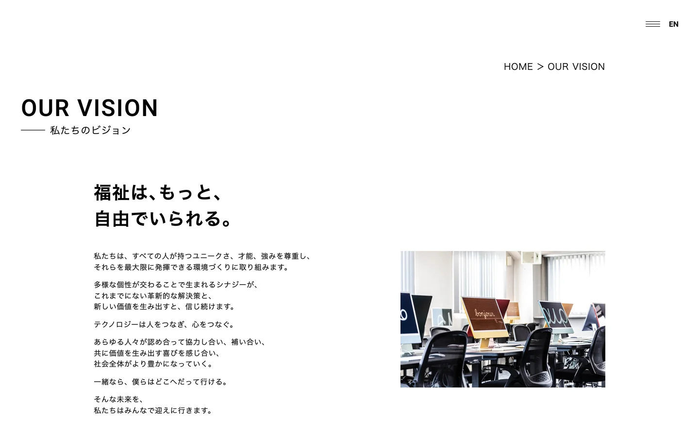 ビジョンのページのPC画面。「OUR VISION 私たちのビジョン」の見出し、「福祉は、もっと、自由でいられる。」の見出しと文章、パソコンが並ぶオフィスの写真